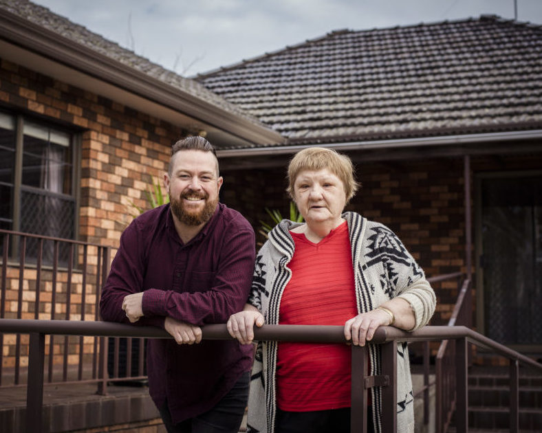 A Civic accommodation staff member and client posing for a picture in front of a home.