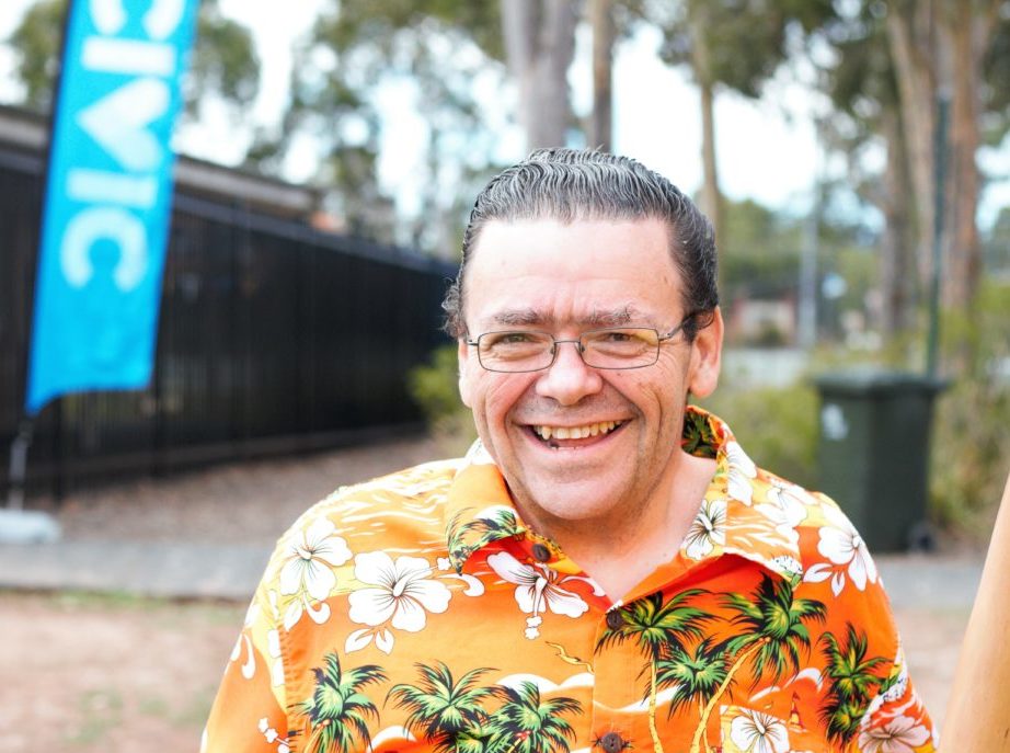 Civic client wearing a bright orange island shirt, smiling for a picture.