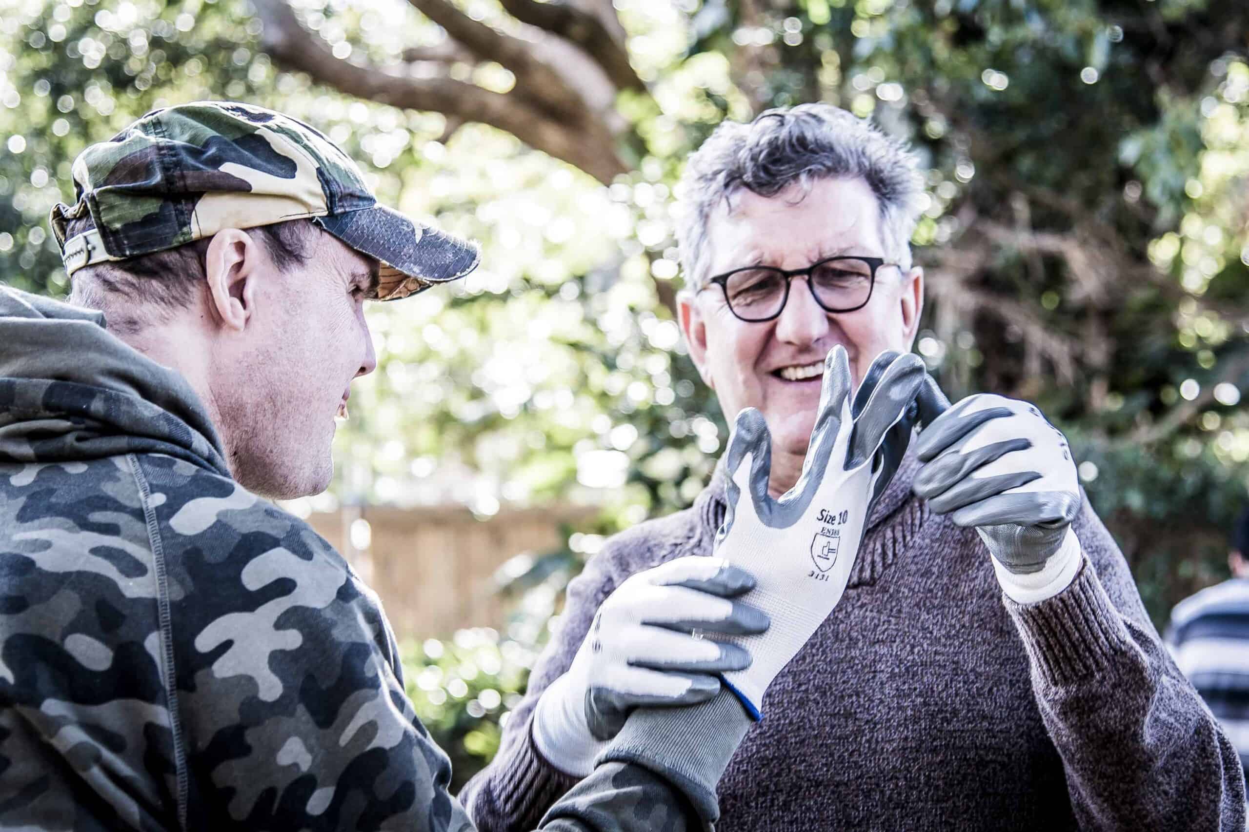 Civic staff member helping a Civic client to adjust his gardening clove.