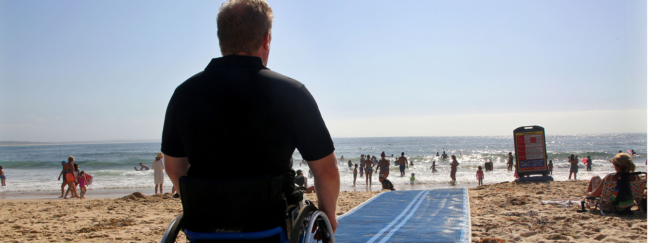 physically disabled man sitting in his wheel chair at the beach.