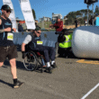 Image shows Civic Champion in wheelchair crossing the finish line of the Sutherland to Surf with Civic volunteer